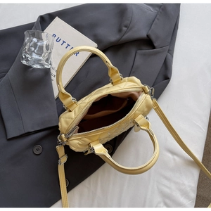 Detail of yellow quilted Boston bag with silver rhinestones on a stylish grey blazer