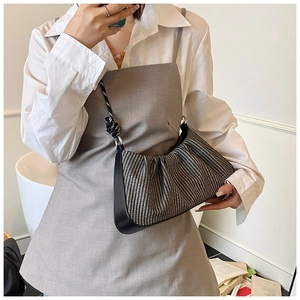 Detail of woven cloud bag texture and black leather strap with white knot design
