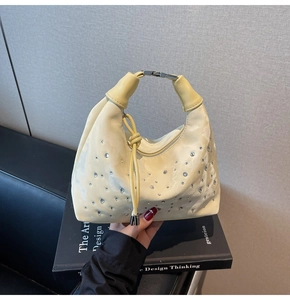 Close-up of cream textured handbag featuring silver rhinestone studs and metal buckle