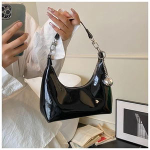 Détail du sac croissant en cuir verni noir brillant avec fermeture éclair argentée et bijou