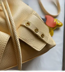 Detail of yellow pebble leather bucket bag featuring gold metal eyelets and soft texture