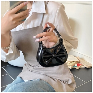 Detail einer schwarzen Lackleder-Mini-Tasche mit großer Schleife und Glanzeffekt