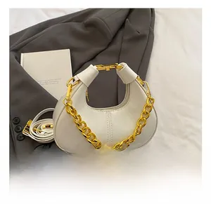Detail of white glossy dumpling bag with chunky gold chain and thin shoulder strap