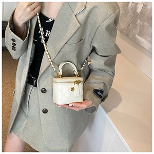 Detailed view of mini white quilted bag with gold flower clasp and chain strap