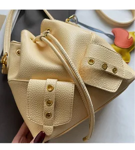 Detail view of beige bucket bag showing litchi grain texture and metal eyelets with drawstring