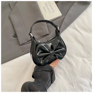 Detailansicht der schwarzen Lackleder-Mini-Tasche mit großer Schleife und Reißverschluss