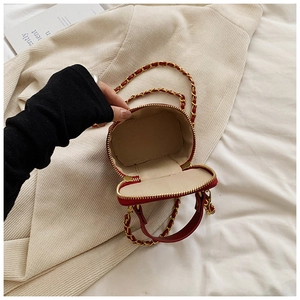 Close-up of red leather mini bag with gold dual zipper and chain strap detail