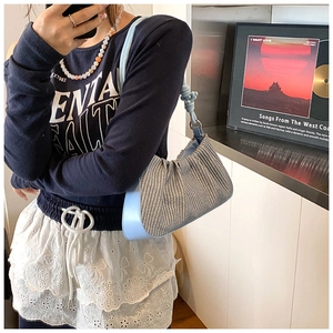 Detailed view of light blue woven underarm bag with leather trim and knotted handle detail