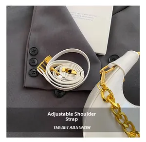 Close-up of white patent leather bag featuring adjustable strap and gold chain detail