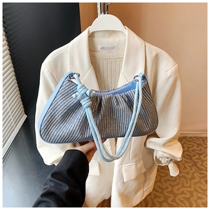 Detail of light blue and white woven shoulder bag with knotted strap and pleated top