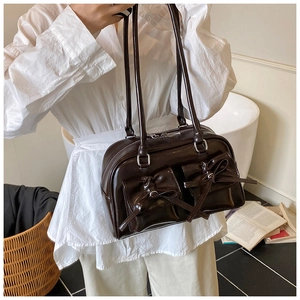 Detail of dark brown glossy leather shoulder bag with decorative bows and double pockets
