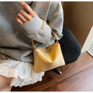 Detailed view of bright yellow crescent shoulder bag worn on the shoulder of a model