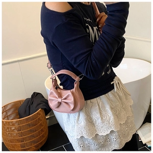 Nahaufnahme einer rosa Mini-Schleifentasche aus glänzendem PU-Leder mit Umhängeriemen