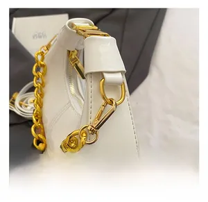 Detail of premium golden metal hook and shiny white patent leather on handbag