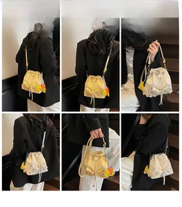 Detail of ivory drawstring bucket bag with bow and colorful elephant charm decoration
