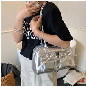 Detailed close-up of metallic silver bowling bag featuring bow accents and twin flap pockets