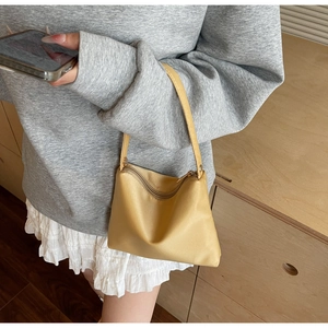 Detail of a bright yellow mini nylon tote bag being carried as a stylish underarm bag