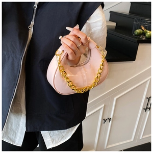 Close-up of light pink glossy moon bag with chunky gold chain strap and top handle