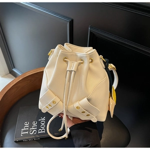 Detail view of cream bucket bag showing lychee pattern leather and gold metal eyelets
