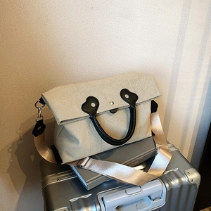 Versatile beige canvas tote bag with black handles and wide shoulder strap for commuting
