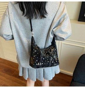 Detail of black pleated tote bag with silver studs worn with a casual gray outfit