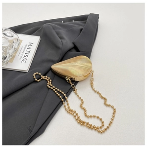 Detailansicht der goldene Abendtasche in Muschelform mit Metallrippen und Kettenriemen