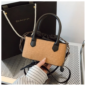 Detail of straw woven bag with black leather handle and secure drawstring inner lining