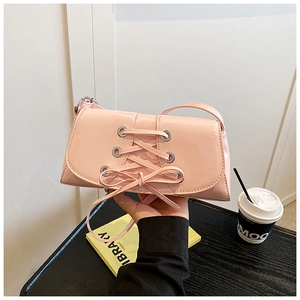 Pink patent leather underarm bag with decorative lace-up straps and silver metal eyelets