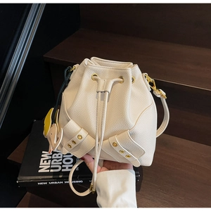 Detail of white lychee grain leather bucket bag with gold rivets and elephant charm