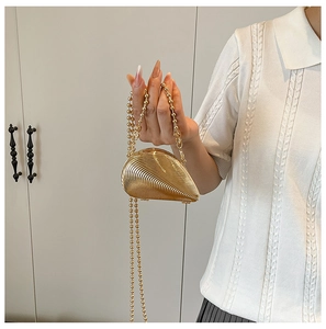 Detaillierte Nahaufnahme einer goldenen Muschel-Abendtasche mit Wellenmuster und Kette