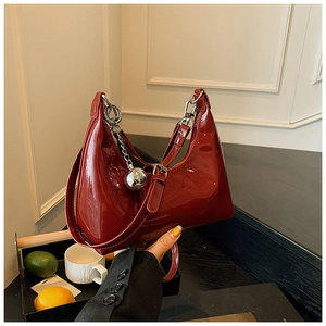 Détail du sac croissant en cuir verni bordeaux avec breloque sphérique argentée
