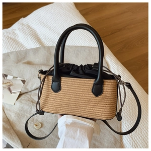 Detail of straw handbag featuring black leather handles and interior drawstring pouch