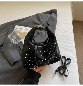 Detail of black pleated dumpling bag featuring silver rhinestones and metal buckle