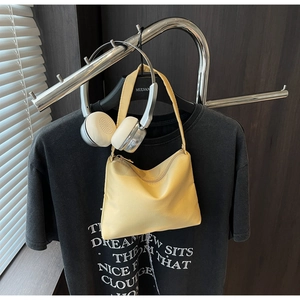 Detail of light yellow crescent shoulder bag featuring smooth fabric and golden metal zipper