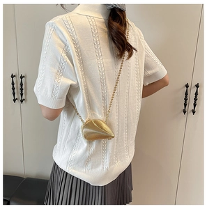 Detail einer metallisch goldenen Muschel-Clutch mit feiner Kette und gerippter Oberfläche