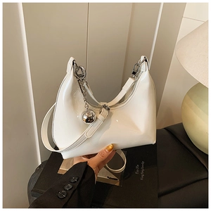Détail du sac croissant en cuir verni blanc avec chaîne et pendentif en métal