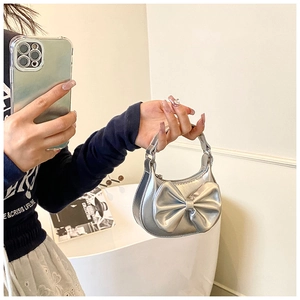 Nahaufnahme einer silbernen Mini-Handtasche mit großer Schleife und Tragegriff