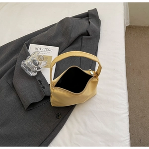 Detailed top view of a light yellow handbag showing gold zipper and black inner lining