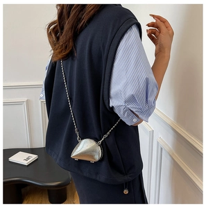 Detail der silbernen muschelförmigen Mini-Tasche mit Metalltextur und Kette