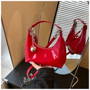Détail du sac croissant en cuir verni rouge avec breloque boule argentée et chaîne