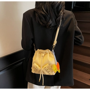 Detail of cream drawstring bucket bag with double pockets and elephant charm decoration