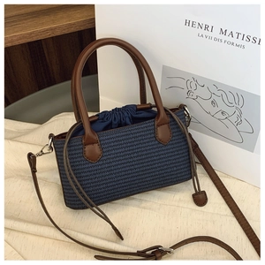 Detailed close-up of woven blue fabric texture and brown leather straps on a beach bag