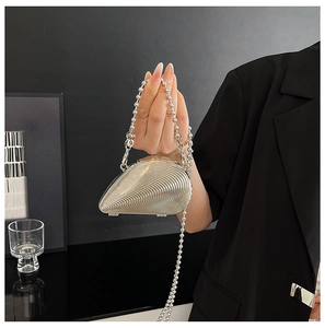Nahaufnahme einer silbernen Muschel-Abendtasche mit plissierter Metallic-Struktur und Kette
