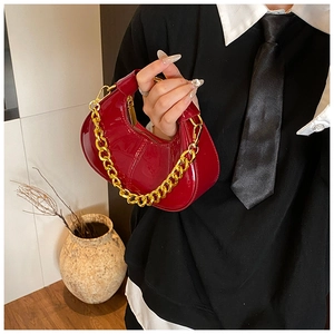 Detail of red patent leather dumpling bag with chunky gold chain handle and zipper