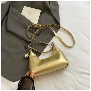 Détail du sac croissant en cuir verni brillant avec pendentif boule argentée et sangle