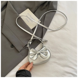 Detaillierte Nahaufnahme einer silbernen Mini-Tasche mit Schleife und Umhängeriemen