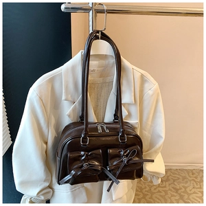 Detail of dark brown glossy leather handbag with bow accents and dual front pockets