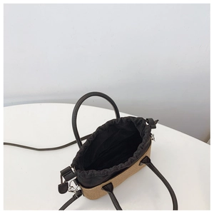 Top view of woven straw tote bag showing internal drawstring closure and leather handles