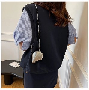 Detailansicht der silbernen Muscheltasche mit filigraner Metallkugelkette am Rücken getragen