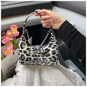 Detail of glossy leopard print handbag with silver chain strap shown in car interior
